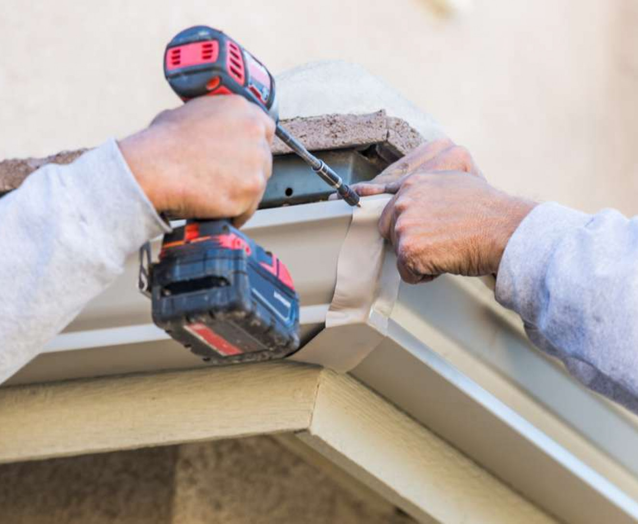 A sunlit brick wall of a commercial building with a smooth concrete pathway and blue sky above. Security cameras are mounted on the wall.